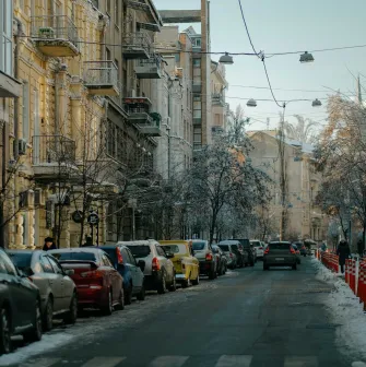 Cars parked along a snowy street with historic buildings in Kyiv