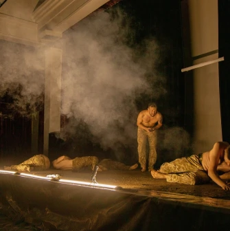 Teatr Voiennykh Dii in Kyiv - intense scene with actors crawling on the dark stage amidst smoke and light beams