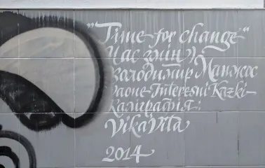 Time of Changes in Kyiv - tile on the wall with a white calligraphic caption of the mural