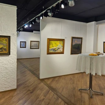 Muzei Suchasnoho Mystetstva in Kyiv - cozy gallery corner with textured white brick walls featuring landscape paintings