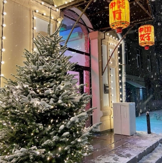 Restaurant Kytaiskyi Pryvit - restaurant entrance decorated with a snowy fir tree and lanterns