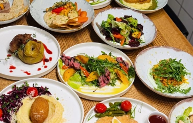 Trishky Bilshe – table with assorted dishes and colorful salads on white plates