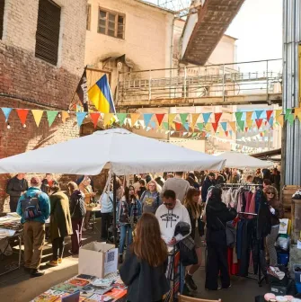 The Podilsky Shuk vintage street market in Podil with clothes, the Ukrainian flag, and visitors