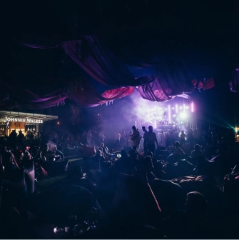 Art-zavod Platforma in Kyiv - outdoor lounge area with bean bags and fabric draping bathed in mystical purple light near a bar