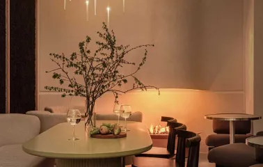 Dinner setting under multiple modern linear pendant lights creating a warm glow