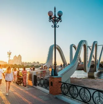 Azov Wave Bridge in Kyiv - pedestrians walking on a wavy bridge bathed in the golden light of the sunset