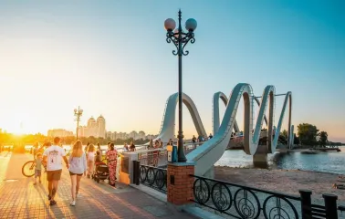 Azov Wave Bridge in Kyiv - pedestrians walking on a wavy bridge bathed in the golden light of the sunset