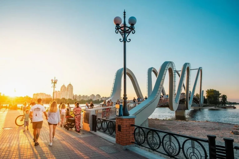 Azov Wave Bridge in Kyiv - pedestrians walking on a wavy bridge bathed in the golden light of the sunset