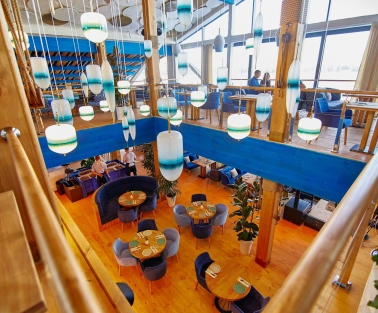 Restaurant Prychal - multi-level dining hall with wooden floors and unique hanging blue lamps