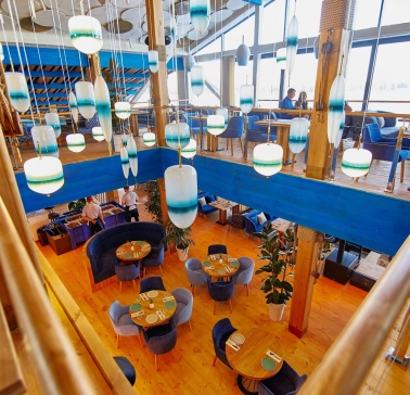 Restaurant Prychal - multi-level dining hall with wooden floors and unique hanging blue lamps