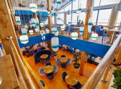 Restaurant Prychal - multi-level dining hall with wooden floors and unique hanging blue lamps