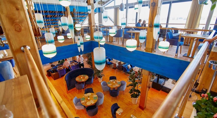 Restaurant Prychal - multi-level dining hall with wooden floors and unique hanging blue lamps