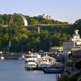 Glass Bridge and Arch of Freedom visible above the River Station building and boats