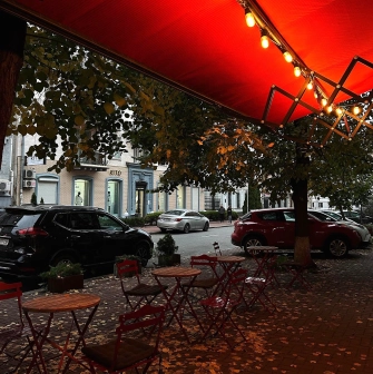Svit Kavy in Kyiv - sidewalk seating under red lit awning with autumn leaves