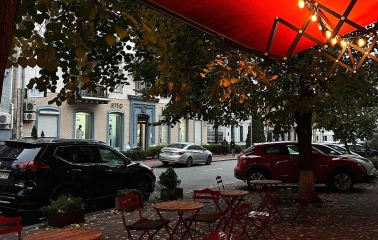 Svit Kavy in Kyiv - sidewalk seating under red lit awning with autumn leaves