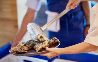 Restaurant Prychal - chef placing fresh raw oysters onto a serving plate with a slotted spoon