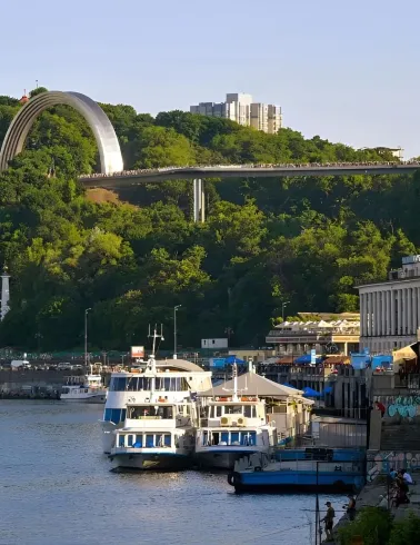 Glass Bridge and Arch of Freedom visible above the River Station building and boats