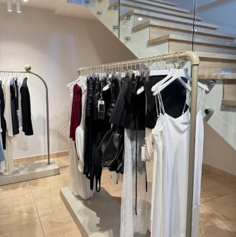 Concept 1 Boutique in Kyiv - stylish clothing rack featuring silk garments next to a modern wooden staircase with glass railings