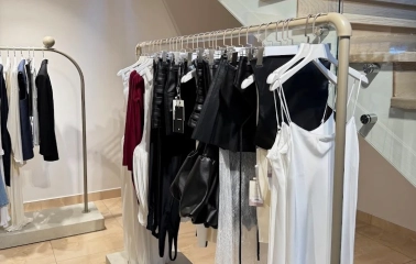 Concept 1 Boutique in Kyiv - stylish clothing rack featuring silk garments next to a modern wooden staircase with glass railings