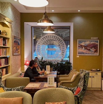 Restaurant Imbyr - restaurant seating area with armchairs a bookcase and natural light from the window