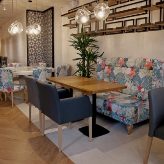 Restaurant Italiets iz Beiruta - seating area with a floral sofa booth and small wooden tables