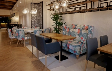 Restaurant Italiets iz Beiruta - seating area with a floral sofa booth and small wooden tables