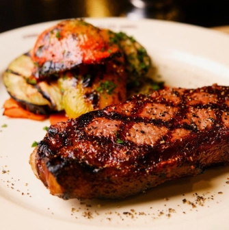 Goodman Steak House - close-up view of a perfectly grilled steak served on a hot skillet