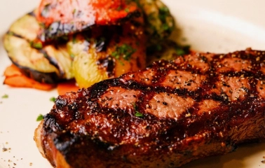 Goodman Steak House - close-up view of a perfectly grilled steak served on a hot skillet
