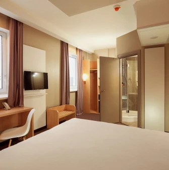 Ibis Railway Station in Kyiv - bedroom interior with white bed and open door