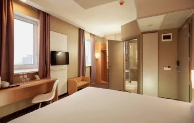 Ibis Railway Station in Kyiv - bedroom interior with white bed and open door