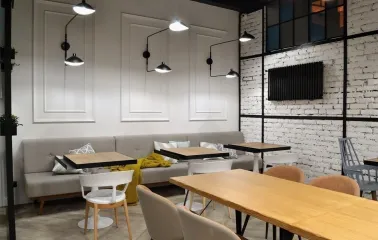 Honey in Kyiv - dining area with grey sofas, white wall and black lamps