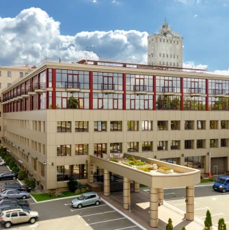 Verkhnii Val in Kyiv - modern beige business center building with red window frames and a parking lot