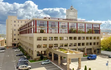 Verkhnii Val in Kyiv - modern beige business center building with red window frames and a parking lot