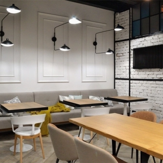 Honey in Kyiv - dining area with grey sofas, white wall and black lamps
