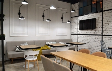 Honey in Kyiv - dining area with grey sofas, white wall and black lamps