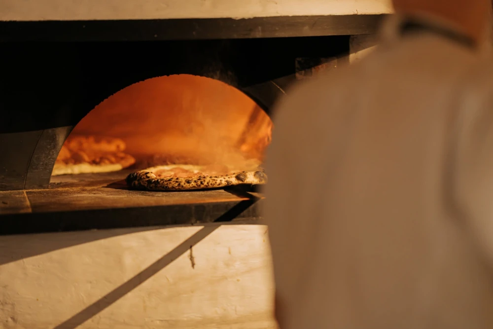 Baking pizza in the wood-fired oven at Tisto, Syr ta titka Bella