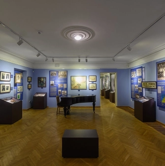 Muzei Ukrainskoi Diaspory in Kyiv - atmospheric blue hall featuring a black grand piano in the center surrounded by framed art and display cases