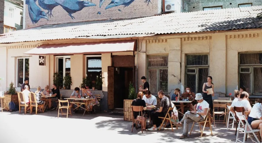 Kashtan - sunny outdoor patio with people dining under a mural of birds