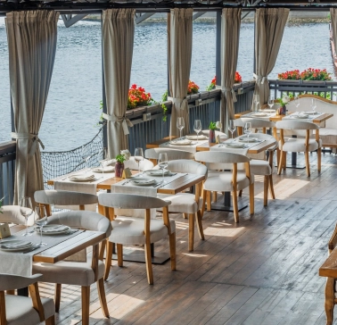 Restaurant Khutorets na Dnipri - waterfront terrace with white dining chairs and river view