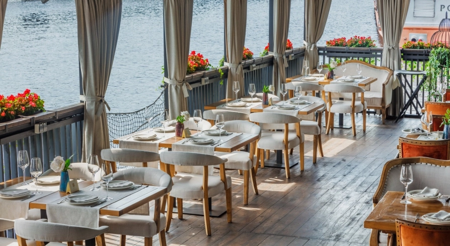 Restaurant Khutorets na Dnipri - waterfront terrace with white dining chairs and river view