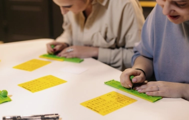 Muzei u Temriavi in Kyiv - close-up of visitors learning to write Braille using a stylus and slate during an educational workshop