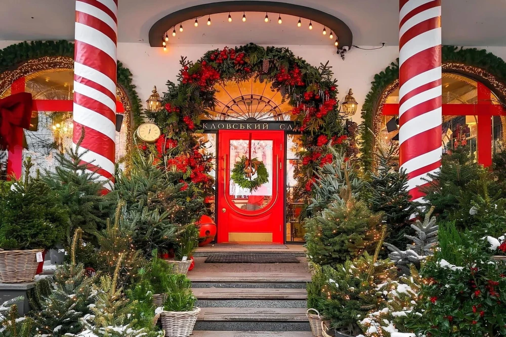 Klovskyi Sad in Kyiv - festive winter entrance decorated with Christmas wreaths, lights and fir trees around a bright red door