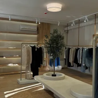 Concept 1 Boutique in Kyiv - spacious showroom interior designed in beige tones with a decorative olive tree in the center