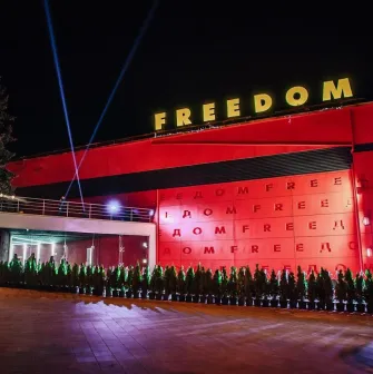 Freedom Hall in Kyiv - bright red facade with yellow neon letters and spotlights beaming into the night sky