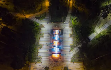Park Partyzanskoi Slavy in Kyiv - aerial night view of the park's central alley featuring the glowing geometric fountain complex surrounded by dark forest trees