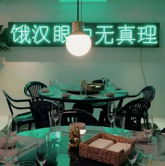 Restaurant Kytaiskyi Pryvit - dining tables set with dishes under a neon sign and light fixture