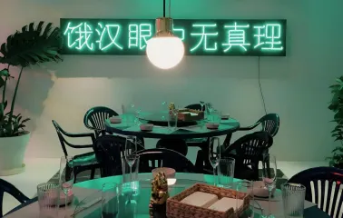 Restaurant Kytaiskyi Pryvit - dining tables set with dishes under a neon sign and light fixture