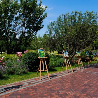 Paintings on easels displayed along a pathway in the park of the Mezhyhirya Residence