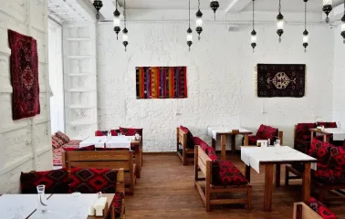 Musafir - cozy dining room with white brick walls and patterned cushions