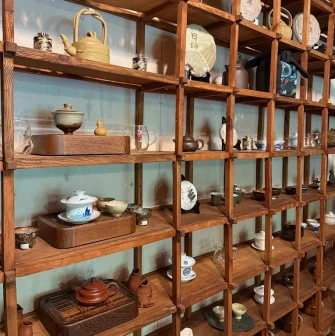 Chaguan in Kyiv - wooden shelves displaying clay teapots and bowls